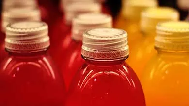 Rows of sealed beverage bottles filled with red, orange, and yellow liquids, highlighting packaged drink preservation.