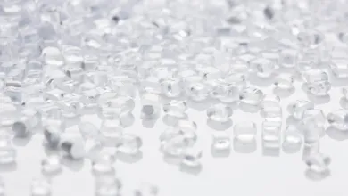 Clear plastic pellets scattered across a white surface.