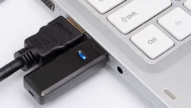 Close‑up of a laptop with multiple cables and adapters connected to its ports.