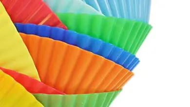 Colorful ribbed silicone baking cups in yellow, red, orange, blue, green, and light blue, arranged in an overlapping fan shape on a white background.